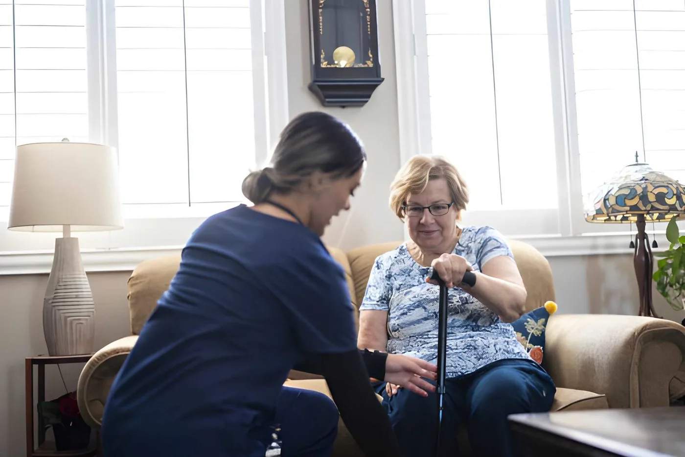 A caregiver speaking with an older woman who uses a walking cane